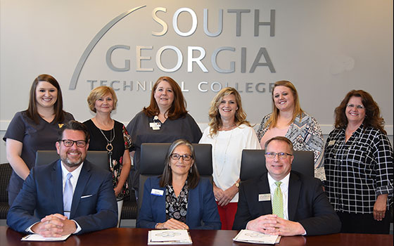 SGTC Staff members in front of SGTC logo on the wall behind them